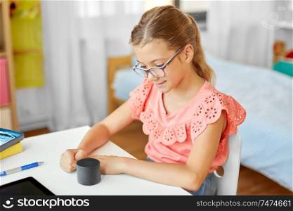 children, education and technology concept - student girl using smart speaker at home. student girl using smart speaker at home