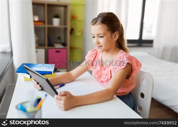 children, education and technology concept - student girl using tablet computer at home. student girl using tablet computer at home