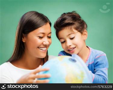 children, education, geography, school and happy people concept - happy teacher and girl with globe over green chalk board background