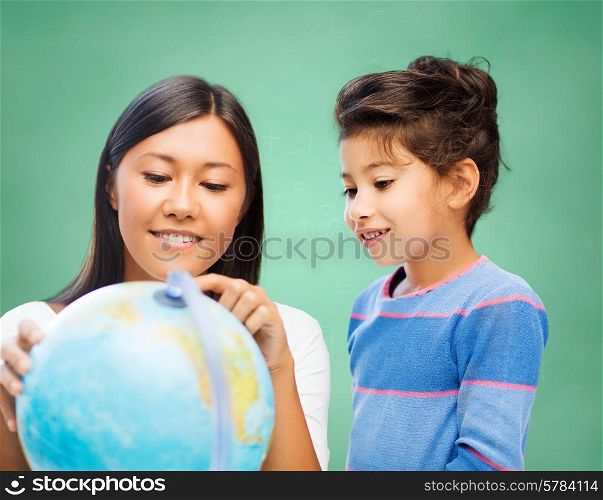 children, education, geography, school and happy people concept - happy teacher and girl with globe over green chalk board background