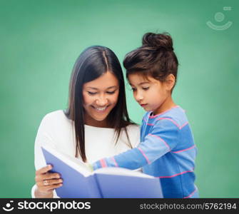 children, education, school and happy people concept - happy teacher and little schoolgirl reading book over green chalk board background