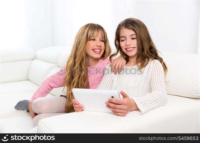 Children friends kid girls playing together with tablet pc on white sofa