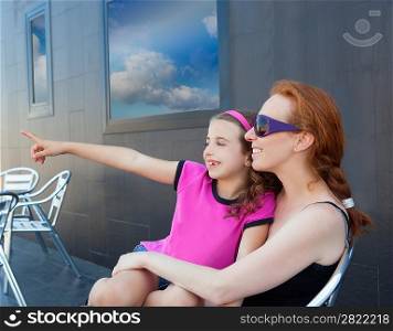 Children girl daughter sitting on mother lap pointing finger away