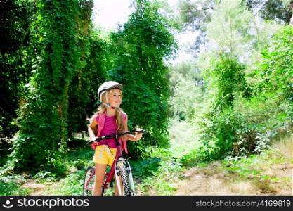 Children girl riding bicycle outdoor in forest smiling with helmet