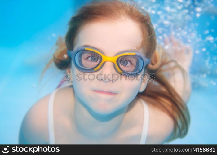 children girl swimming underwater with goggles and funny gesture