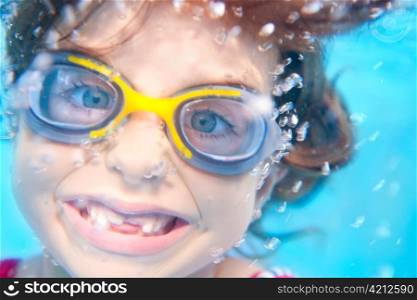 children girl swimming underwater with goggles and funny gesture