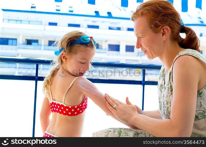 children girl with mother applying sunscreen in summer