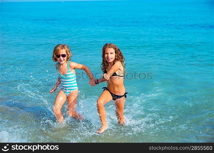 children girls friends running together in the beach shore on summer vacation