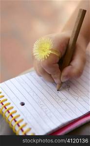Children hand with funny yellow ring writing on a notebook