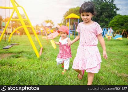 Children having fun little girl holding hand together with love playing outside Asian kids happy in the garden park with playground / International Children?s Day