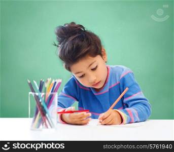 children, hobby, childhood and happy people concept - little girl drawing over green chalk board background