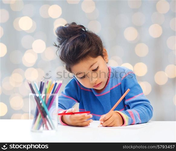 children, hobby, childhood and happy people concept - little girl drawing over holidays lights background