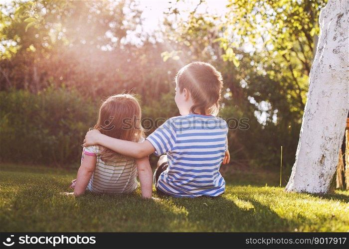 children hugging in the garden at the sunset. brother with his little sister outdoor back