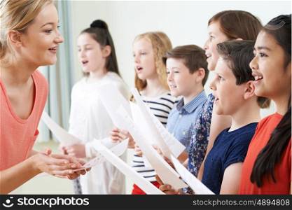 Children In School Choir Being Encouraged By Teacher