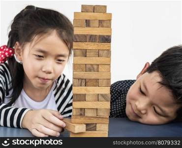 Children is playing a wood blocks tower game for practicing their physical and mental skill