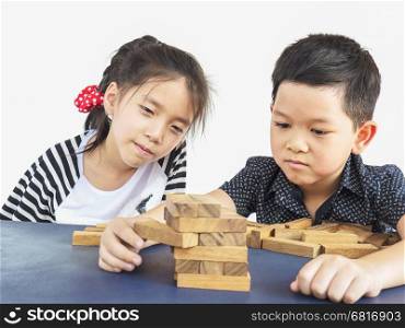 Children is playing jenga, a wood blocks tower game for practicing their physical and mental skill