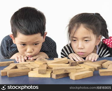 Children is playing jenga, a wood blocks tower game for practicing their physical and mental skill