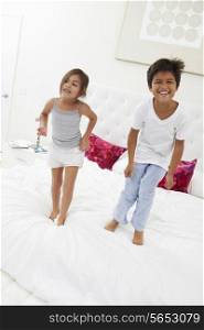 Children Jumping On Bed In Pajamas Together