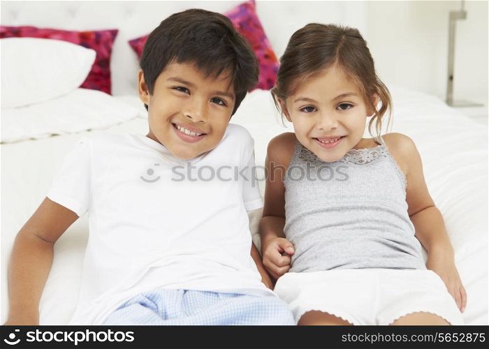 Children Lying On Bed In Pajamas Together