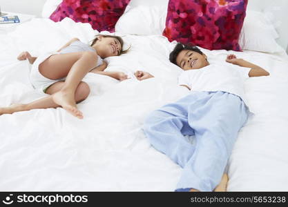 Children Lying On Bed In Pajamas Together