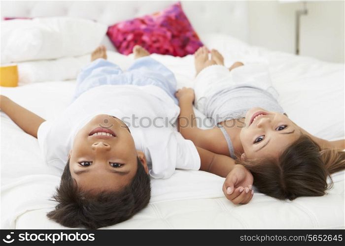 Children Lying Upside Down On Bed In Pajamas Together