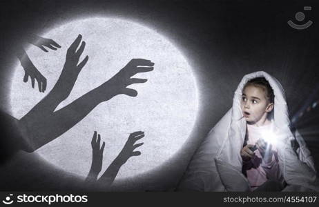 Children nightmare. Cute girl in bed under blanket with flash light