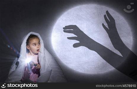 Children nightmare. Cute girl in bed under blanket with flash light