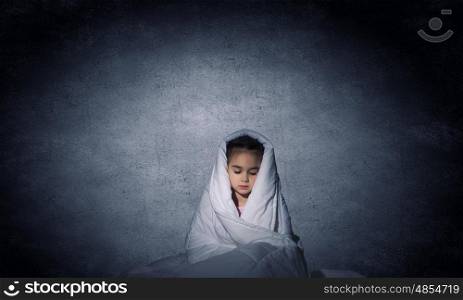 Children nightmare. Cute scared girl sitting in bed under blanket
