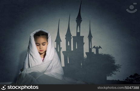 Children nightmare. Cute scared girl sitting in bed under blanket