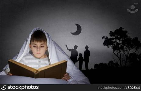 Children nightmare. Little cute boy sitting in bed under blanket with book
