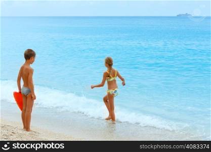 Children on summer Egremni beach and ship on horizon (Lefkada, Greece)