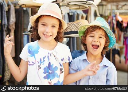 Children On Vacation Trying On Hats At Store