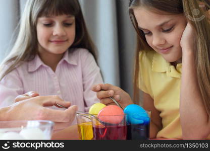 Children paint chicken eggs in different colors.