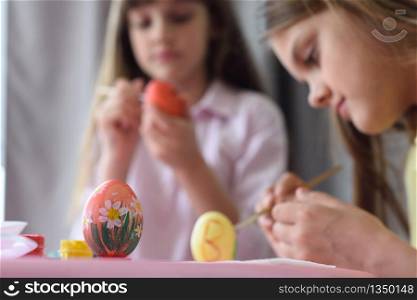 Children paint Easter eggs, focus on the egg in front of them