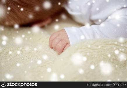 children, people and care concept - close up of baby lying on soft furry blanket over snow. close up of baby lying on soft furry blanket