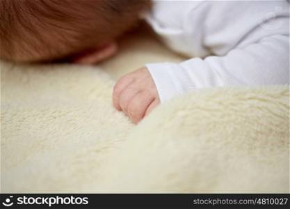 children, people and care concept - close up of baby lying on soft furry blanket