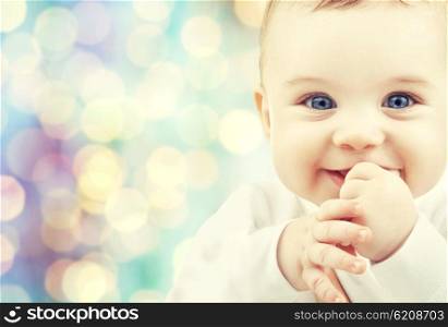 children, people, infancy and age concept - beautiful happy baby boy over blue holidays lights background