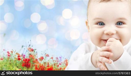 children, people, infancy and age concept - beautiful happy baby over blue lights and poppy field background