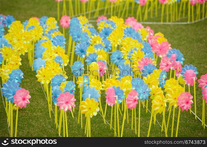 Children pinwheels on grass. Yellow, blue and red pinwheels on a meadow