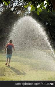Children play with jets of water in hot weather. Play with water jets