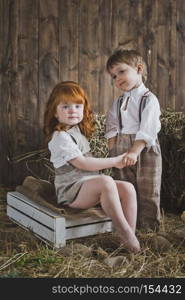 Children playing holding hands.. Children holding hands on the background of wooden walls and hay 6087.