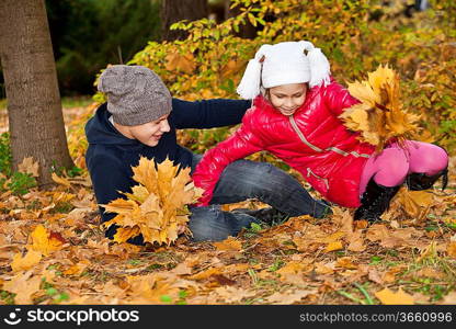 Children playing with autumn fallen leaves in park