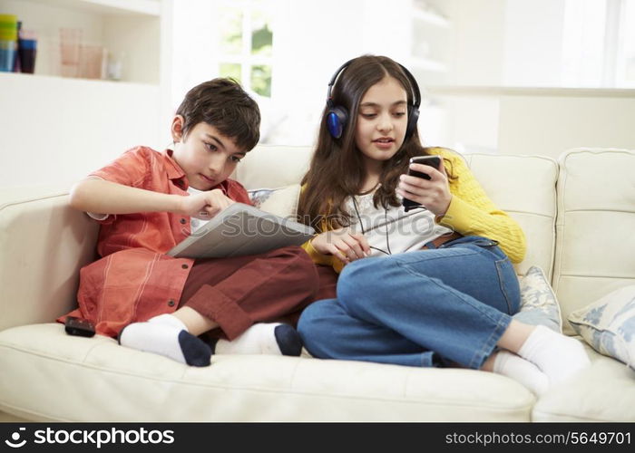 Children Playing With Digital Tablet And MP3 Player