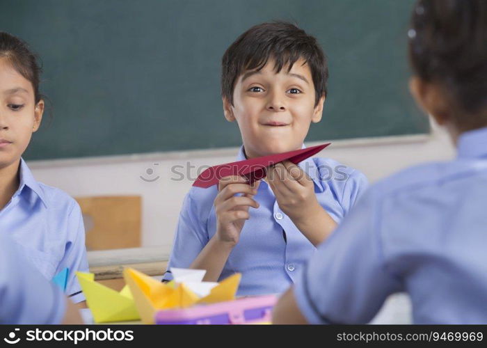 children playing with paper plane and boat in class