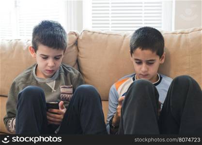 Children playing with their smartphones. Two boys with mobile phones