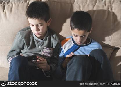 Children playing with their smartphones. Two boys with mobile phones