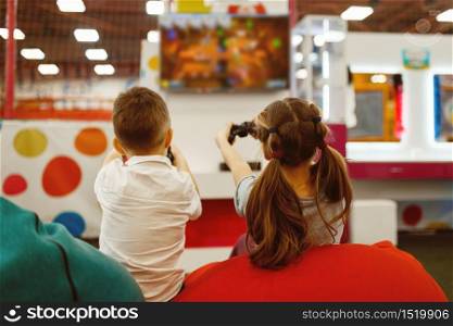 Children plays a game console in the entertainment center. Girl and boy leisures on holidays, childhood happiness, happy children. Children plays game console, entertainment center