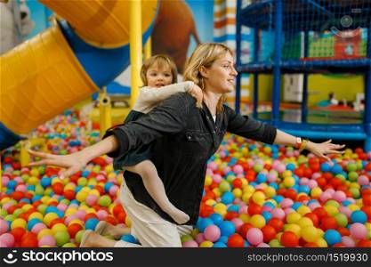 Children plays with mother in the entertainment center. Mom and her daughter leisures on holidays, childhood happiness, happy kids on playground. Children plays with mother in entertainment center