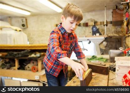 children, profession, carpentry, woodwork and people concept - happy little boy with ruler measuring wood plank at workshop