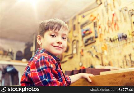 children, profession, carpentry, woodwork and people concept - happy little boy with wood plank at workshop. happy little boy with wood plank at workshop. happy little boy with wood plank at workshop